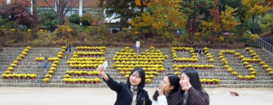 １０日、ソウル女子高の生徒が花文字の前で記念写真を撮っている。