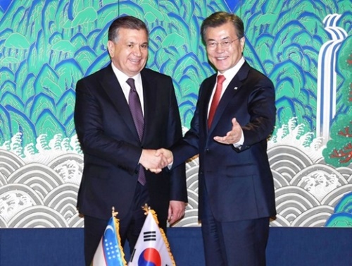 ２３日、韓国の文在寅大統領（左）とウズベキスタンのシャヴカト・ミルズィヤエフ大統領が共同声明に署名したあと、握手をしている。