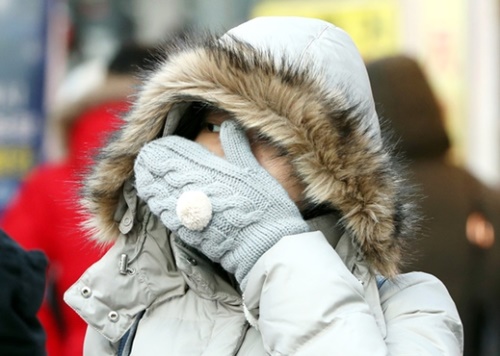 １２日、ソウル明洞で外国人観光客が冷たい風を防ぐために手袋をはめた手で顔を隠している。気象庁は１４日まで寒さが続き、最低気温が氷点下１０度まで下がるところが多いと予報した。
