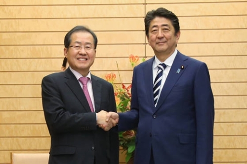 自由韓国党の洪準杓代表（左）が１４日午後、東京の首相官邸で安倍晋三首相と握手をしている。２人はこの日、北核問題の解決に向けた両国間協力案を議論した。（写真＝自由韓国党）