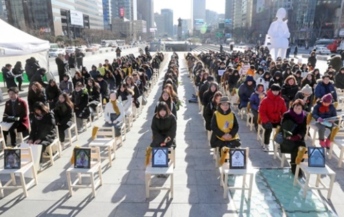 今年最後の「水曜デモ」が２７日、ソウル中学洞の旧駐韓日本大使館前で開かれた。集会の後、光化門広場まで行進した参加者が今年亡くなった８人の慰安婦被害者を追慕する行事を行っている。