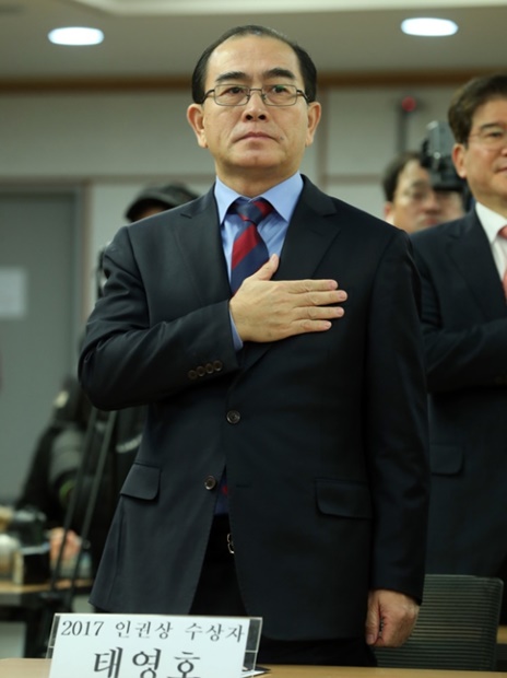 太永浩元駐英北朝鮮公使が韓国の太極旗に向かって国旗に対する敬礼をしている。