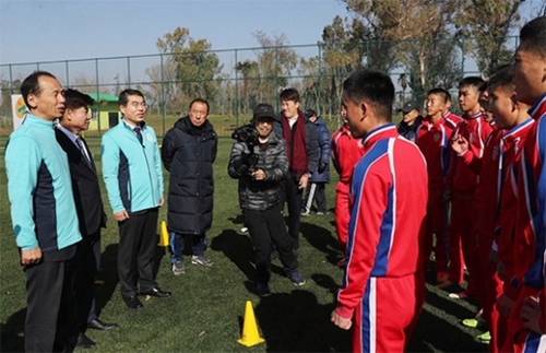 崔文洵（チェ・ムンスン）江原道知事（左）が昨年１２月１９日、中国昆明で開催された国際ユース（Ｕ－１５）サッカー大会に出場した北朝鮮選手と話している。（写真＝江原道）