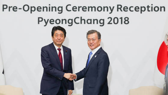 文在寅大統領が９日午後、平昌五輪開会式参加のため訪韓した日本の安倍晋三首相と握手している。（写真＝青瓦台写真記者団）
