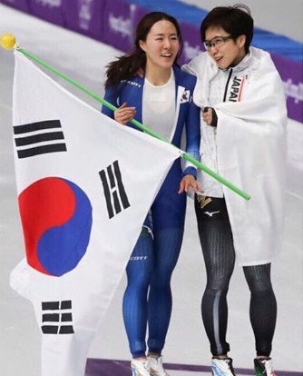 スピードスケート女子５００メートルでレース後、李相花（左）と小平奈緒が肩を寄せ合って笑っている。