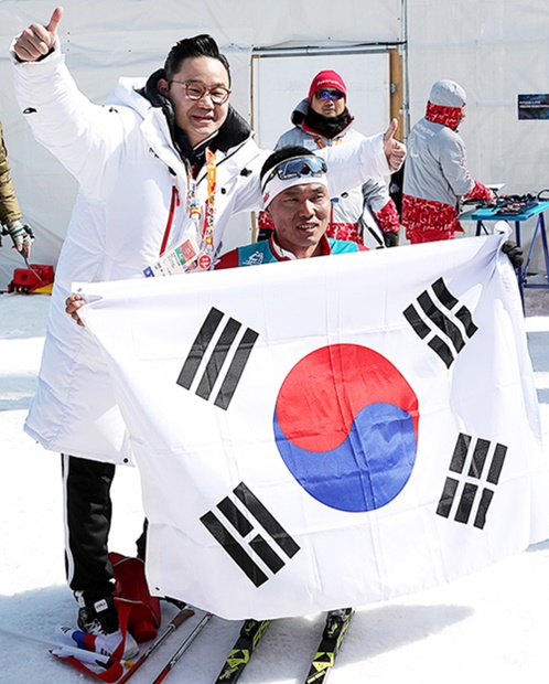 平昌パラリンピックで韓国初メダルを獲得したシン・ウィヒョン選手（手前）がペ・ドンヒョン選手団長と喜びの記念撮影で笑顔を見せている。