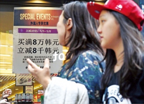韓国を訪れる中国人個人旅行客が増加している。７日、中国人観光客が販促行事内容が掲示されたソウル・明洞のある化粧品ショップの前を通りすぎている。