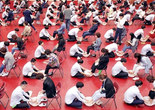 ８日、大田東山高等学校１・２学年の生徒が体育館で両親の足を洗っている。