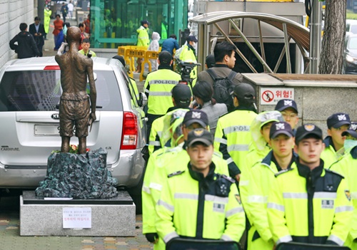 釜山東区の日本総領事館後門近くの歩道中央に強制徴用労働者像が設置される中、警察が労働者像を少女像の横に移せないように乗用車を前に駐車して警察兵役を配置している。