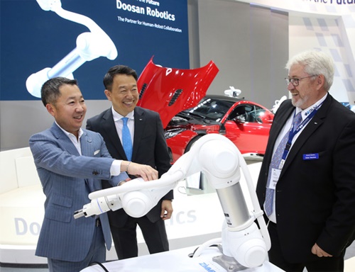 斗山グループの朴廷原会長（左）がドイツ・ミュンヘンで最近開かれた「ＡＵＴＯＭＡＴＩＣＡ　２０１８」で、海外企業家に斗山が作った協同ロボットを説明している。（写真提供＝斗山）