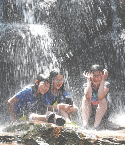 ソウルの気温が３３．２度で今年最高を記録した１５日、京畿道果川市にある冠岳山の渓谷に遊びに来た子どもたちが滝から落ちる水を浴びながら暑さをしのいでいる。