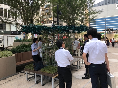 ２３日、東京日比谷で開かれた暑さ対策展で市民が「ミストシャワー」などを試している。東京の都心はこの日、３９度まで気温が上がった。