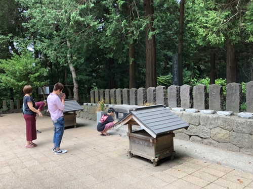 旧会津藩飯盛山の中腹にある少年武士の墓地を観光客が参拝している。自決を図った２０人のうち１人が奇跡的に一命を取り留め、墓地は１９基となっている。