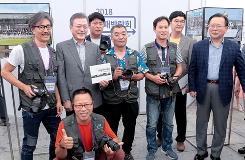 １６日、ソウル光化門広場で開かれた「２０１８失敗博覧会」を訪れ、ホームレス出身の写真作家らと記念撮影をしている文在寅大統領（左から２人目）。