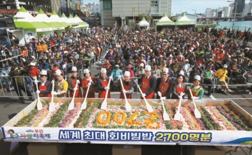 １４日午後、釜山中区にあるチャガルチ市場で開かれた「第２７回チャガルチ祭り」で、ゲストが２７００人分の刺し身ビビンパの前でポーズを取っている。