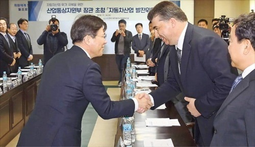 自動車メーカーと自動車部品メーカー、韓国政府関係者らが１４日にソウルの韓国自動車産業協同組合会議室で額を突き合わせ自動車産業の危機克服対策を議論した。成允模産業通商資源部長官（前列左）とカハー・カゼム韓国ＧＭ社長が会議に先立ち握手している。