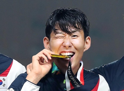 孫興民（ソン・フンミン）がアジア競技大会サッカーの表彰式で金メダルをかんでいる。