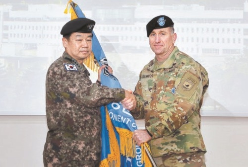 鄭景斗（チョン・ギョンドゥ）国防部長官（右）がキム司令官に部隊旗を渡している。