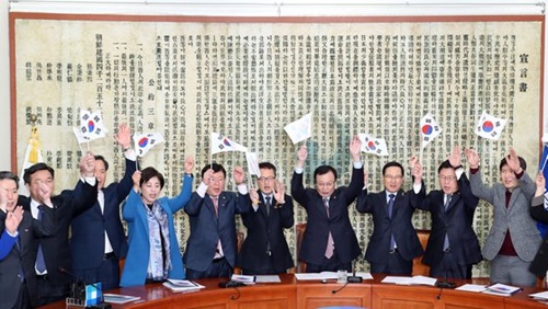 韓国与党「共に民主党」の李海チャン代表（右から４人目）、洪永杓（ホン・ヨンピョ）院内代表らが２５日午前、国会で開かれた最高委員会議に先立ち、三・一独立宣言朗読および万歳再現行事を行い、万歳を叫んでいる。背景にあるのは独立宣言文。