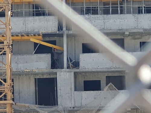 ウラジオストクのある建設現場で２８日（現地時間）、北朝鮮労働者が合板を移動させる作業をしている。安全ヘルメット１つが唯一の安全装置だった。この労働者が立っている場所は建物１１階の高さだ。