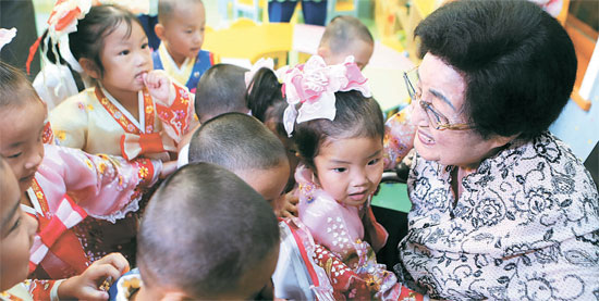 故・李姫鎬さんが平壌（ピョンヤン）のある保育園で子供たちを抱いている。（写真＝金大中平和センター）