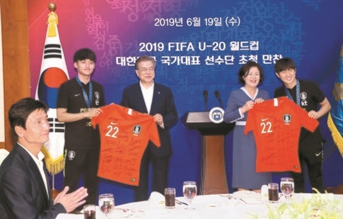 １９日、文在寅大統領と金正淑夫人がＵ－２０サッカー韓国代表のキャプテンであるファン・テヒョン選手（左）と「ゴールデンボール」の主人公イ・ガンイン選手（右）から選手全員の署名が入ったユニフォームを贈られている。（写真＝青瓦台写真記者団）