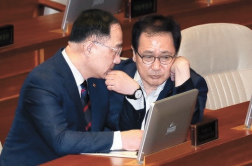 洪楠基（ホン・ナムギ）副首相（左）と兪英民（ユ・ヨンミン）科学技術情報通信部長官が４日、国会で対話している。洪副首相は日本の輸出規制について「明白な経済報復であり、相応の措置を用意する」と述べた。