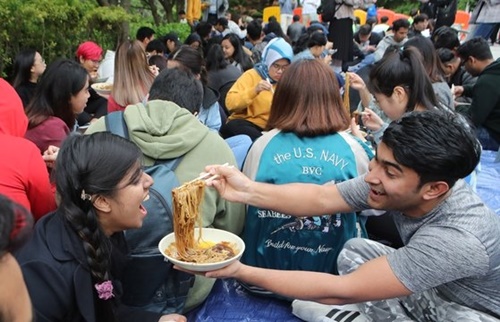 昨年、外国人入国者数が２０００年の統計集計開始以来の最大値を記録した。写真は４月に慶星（キョンソン）大学国際学生支援チームが中間試験で疲れた外国人留学生のために「２０１９年グローバル麺デーイベント」を校内の商学館前で開催し、学生がチャジャンミョン（ジャージャー麺）を食べている様子。ソン・ボングン記者