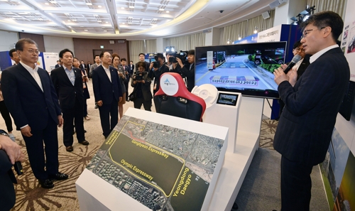 韓国の文在寅（ムン・ジェイン）大統領（左）がＬＧ　Ｕ＋の５Ｇ自動運転車の実演ゾーンで同社のカン・ジョンオ未来技術担当（右）の説明を聞いている。［写真　ＬＧ　Ｕ＋］
