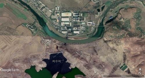 衛星写真に捉えられた北朝鮮の平山ウラン工場。貯水池が工場から放出された廃棄物とされる物質で黒く染まっている。［写真　グーグルアース］