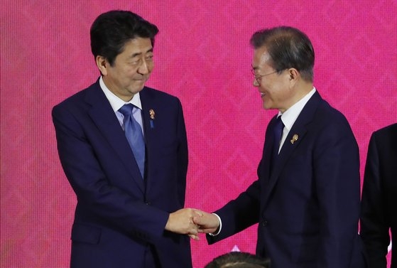 文在寅大統領（右）が先月４日にタイのバンコクで開かれた東アジア地域包括的経済連携（ＲＣＥＰ）首脳会議で日本の安倍晋三首相と握手している。［青瓦台写真記者団］