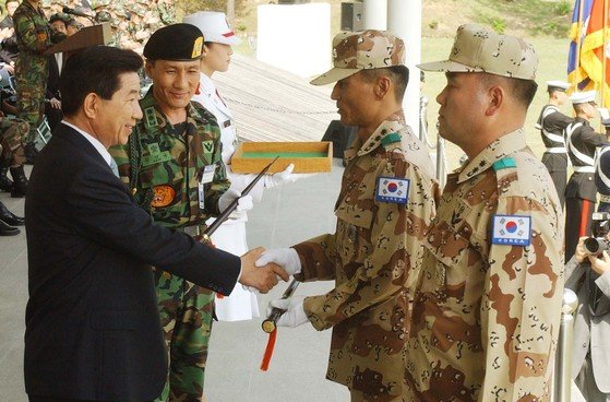 ２００３年４月２８日、イラク派兵申告および歓送行事に参加した盧武鉉元大統領が徐熙（ソヒ）部隊のチェ・グァンヨン大佐に指揮棒を手渡している。［中央フォト］