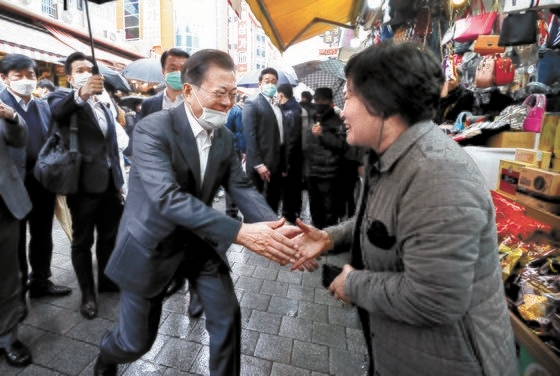 １２日、ソウル南大門市場を訪問して商人と握手をしている文在寅大統領。［写真　青瓦台写真記者団］
