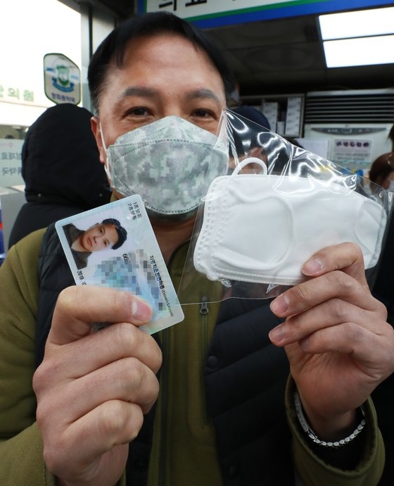 マスク５部制が施行された９日午前、ソウル・鍾路区の薬局で市民が身分証を提示してマスクを購入している。マスク５部制の施行により、薬局では出生年により１週間当たり１人２枚まで購入が可能だ。チェ・ジョンドン記者