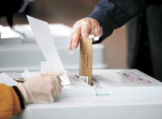 韓国ソウル駅ＫＴＸ待合室に用意された第２１代国会議員選挙ソウル龍山区南営洞（ヨンサング・ナミョンドン）の期日前投票所で投票する有権者。ビニール手袋をはめたまま投票している。新型コロナ防疫対策の一環だ。シン・インソプ記者