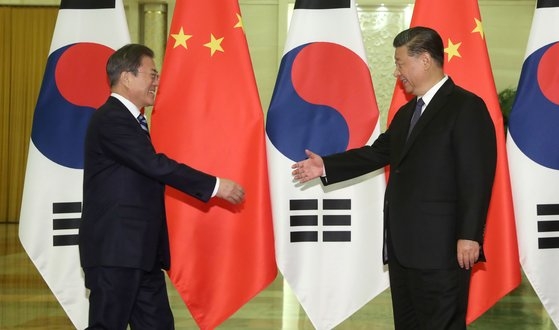 韓国の文在寅大統領（左）が昨年１２月、中国北京人民大会堂で中国の習近平国家主席（右）との首脳会談に先立ち握手をしようとしている。［写真　青瓦台写真記者団］