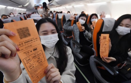 チェジュ航空「仁川ｔｏ仁川」観光飛行の乗客が離陸前に搭乗券を見せながら喜んでいる。［写真　空港写真記者団］