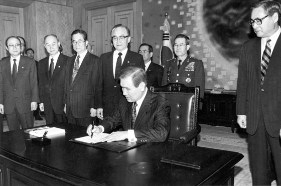 盧泰愚（ノ・テウ）大統領が１９９２年２月１７日、鄭元植（チョン・ウォンシク）首相（右）が見守る中、南北基本合意書と韓半島非核化に関する共同宣言に署名している。　［中央フォト］