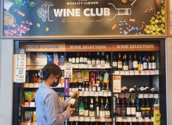 顧客がイーマート２４の店舗でワインを選んでいる。［写真　イーマート２４］