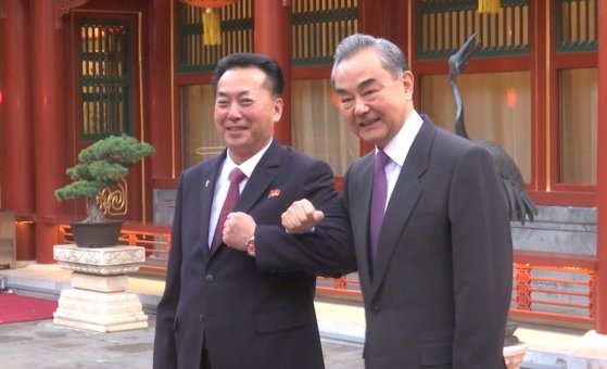 中国の王毅外相（右）が２７日午後に北京の釣魚台国賓館で李竜男駐中北朝鮮大使との会談に先立ち腕組みをして記念撮影している。［写真　中国外交部ホームページ］