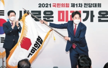１１日に開催された韓国最大野党・国民の力の全党大会で、李俊錫（イ・ジュンソク）代表が金起ヒョン（キム・ギヒョン）院内代表から渡された党旗を振っている。４日間行われた党代表選で９万３３９２票（４３．８％）を獲得して新しい党代表に選出された李俊錫代表は「多様な大統領候補と支持者が共存できる党をつくる」と述べた。　オ・ジョンテク記者