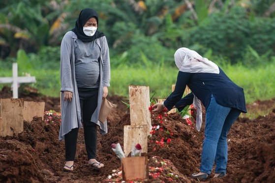 死亡した家族の墓の前で悲しむインドネシア女性。［写真　聯合ニュース］
