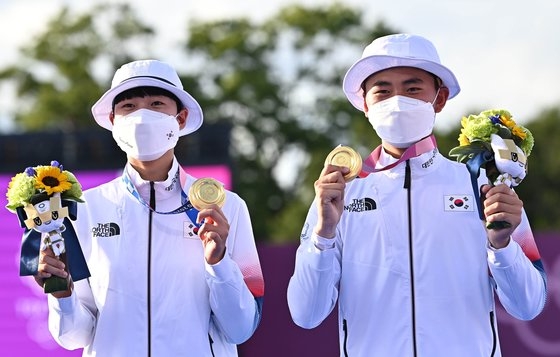 アーチェリー韓国代表のキム・ジェドク（右）とアン・サンが２４日に行われた東京五輪混合団体戦決勝で金メダルを獲得しポーズを取っている。