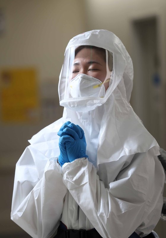 昨年１２月、ソウル中浪区（チュンナング）新型コロナ専門担当病院であるソウル医療院のコ・ノヨン看護師（２５）が感染者の病棟に行く前に保護服を着て祈っている。キム・サンソン記者