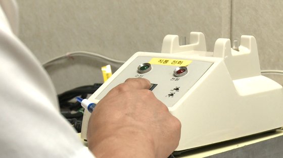南北が１３カ月ぶりに通信連絡線を再稼働した２７日、京畿道坡州市の板門店（パンムンジョム）南北共同連絡事務所で、北朝鮮側連絡代表と通話するため呼び出しボタンを押す韓国側連絡代表。　韓国統一部提供