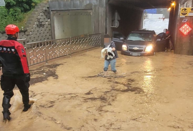 ８日午後、江原道高城（カンウォンド・コソン）で消防隊員が地下車道に孤立した車両の搭乗者５人を救助している。［写真　聯合ニュース］