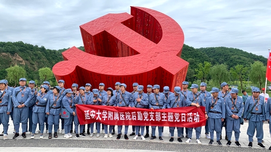 今年６月１９日、陝西省延安の南泥湾開墾地に建てられた中国共産党立体徽章構造物の前で八路軍の服装を着た党員がプラカードを掲げて記念写真を撮影している。シン・キョンジン記者