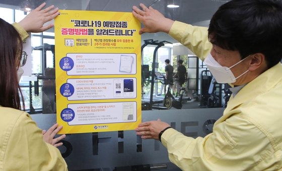 「ワクチン接種者だけジムへの入場可能」…釜山鎮区庁関係者らが２日午後に管内にあるジムで防疫パス（接種証明）案内文を貼り付けている。ソン・ボングン記者