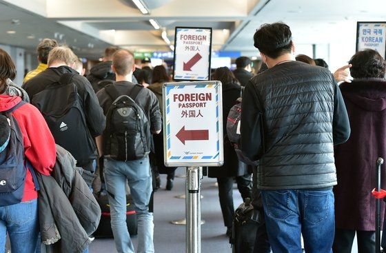 新型コロナウイルスのオミクロン株が世界に急速に広がる中、１１月２９日にハバロフスクとフランクフルトからの入国者らが仁川国際空港に入国して審査を受けている。［写真　空港写真記者団］