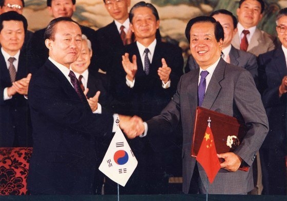１９９２年８月２４日、北京で韓中修交共同声明書を交換して握手を交わす李相玉（イ・サンオク）韓国外相（左）と銭其シン中国外相。　［中央フォト］